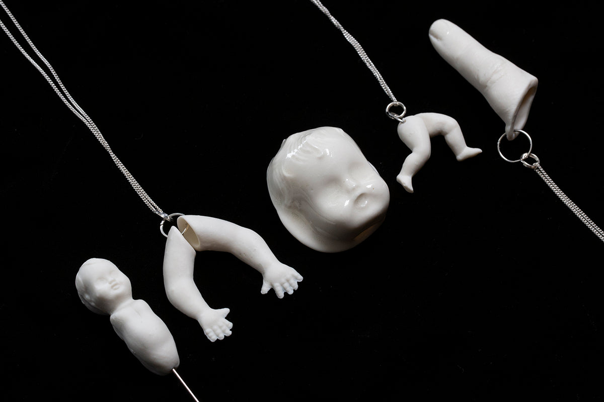 All the porcelain jewellery produced by Martha Todd, for the Uncanny exhibition at the Freud Museum. White porcelain legs, arms, dolls heads and a finger on a black background,